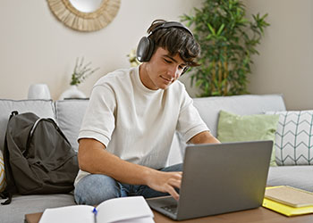 Jeune homme travaillant sur son ordinateur et écoutant de la musique avec un casque
